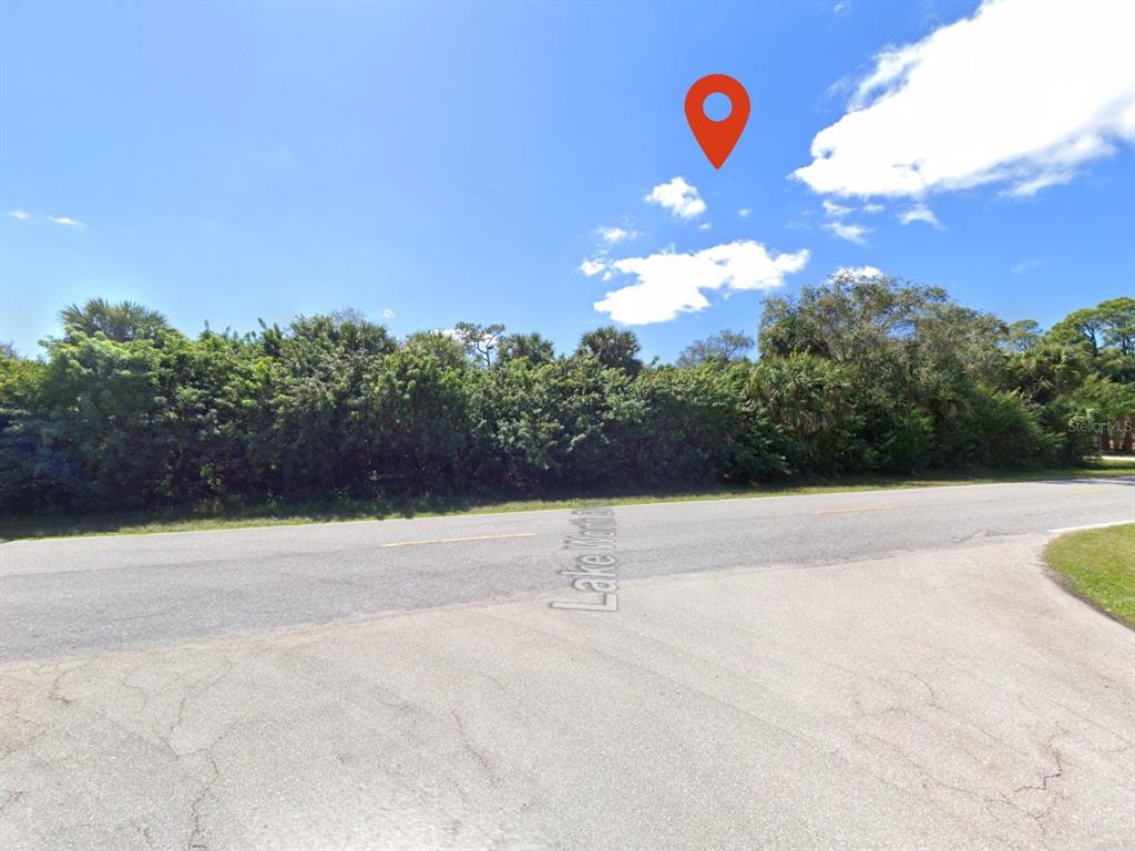 A red map pin marks a vacant, tree-lined lot along a paved road — 18421 LAKE WORTH BOULEVARD, PORT CHARLOTTE, FL