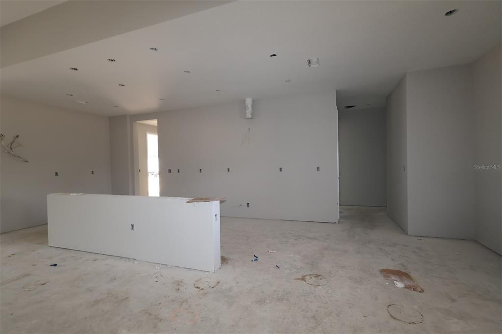 A modern kitchen features white cabinets, a large quartz island, and stainless steel appliances — 3555 WOLVES CREEK PLACE, APOPKA, FL