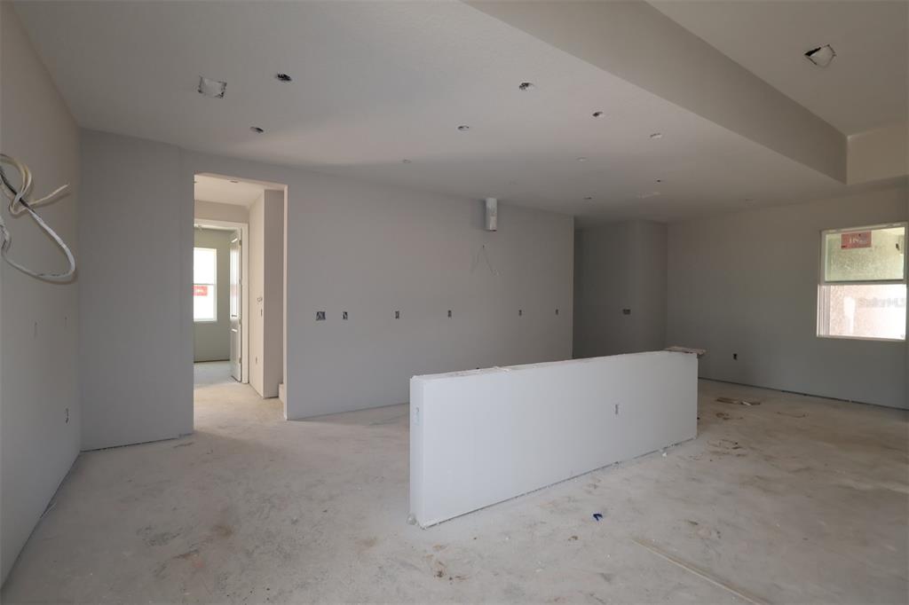 An open-concept kitchen and living area features wood-look tile flooring and sliding glass doors — 3555 WOLVES CREEK PLACE, APOPKA, FL