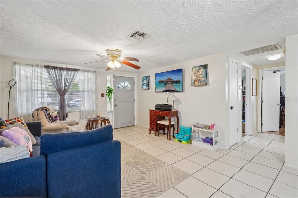A living room features white tile floors, a blue sofa, and a ceiling fan — 2049 MAUREEN DRIVE, HOLIDAY, FL