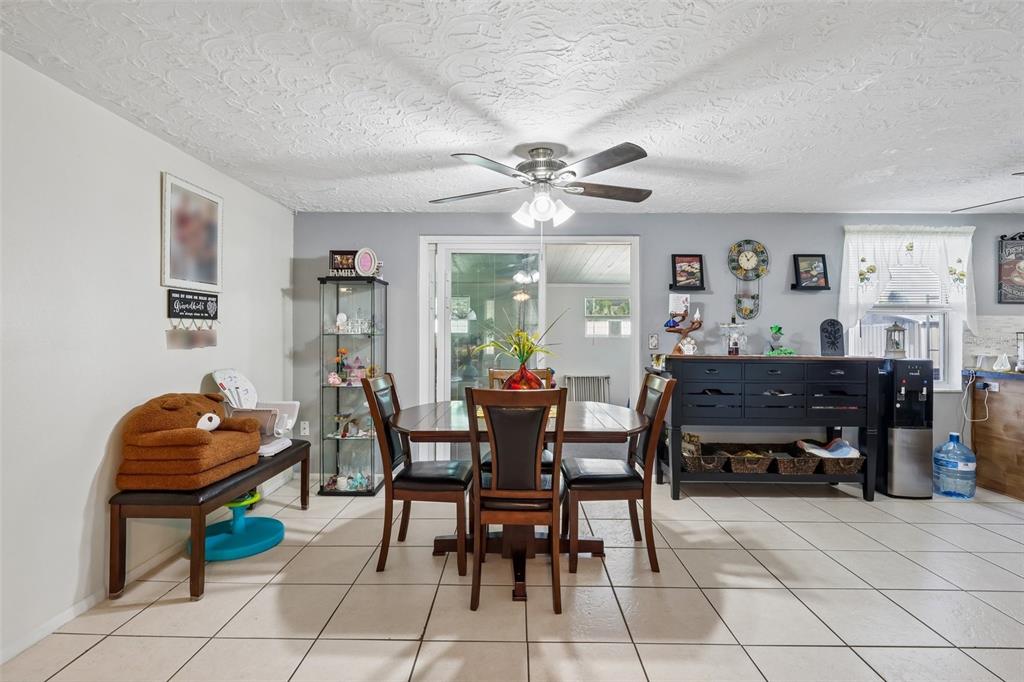 A dining room features a wooden table, four chairs, a glass display cabinet, and tile flooring — 2049 MAUREEN DRIVE, HOLIDAY, FL