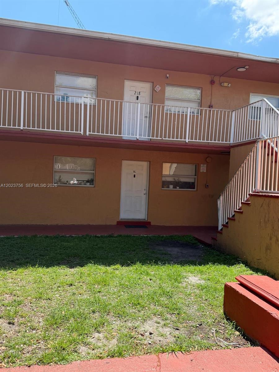 This exterior view shows a two-story apartment building with orange stucco walls and balconies — 1245 W 24th St # 118, Hialeah FL 33010, HIALEAH, FL