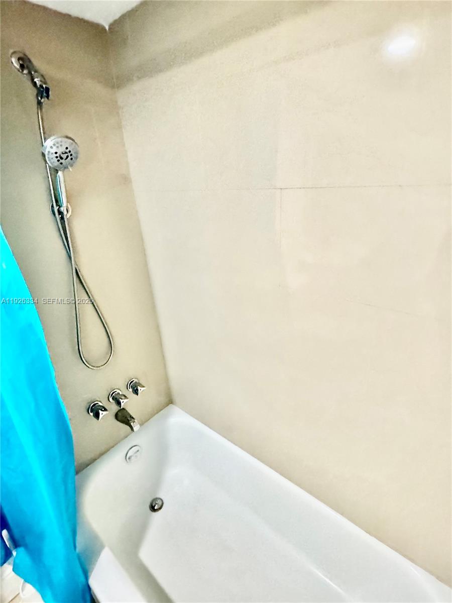 A white bathtub with a handheld shower head and wall-mounted faucet fixtures — 801 Three Islands Blvd # 417, Hallandale Beach FL 33009, HALLANDALE BEACH, FL