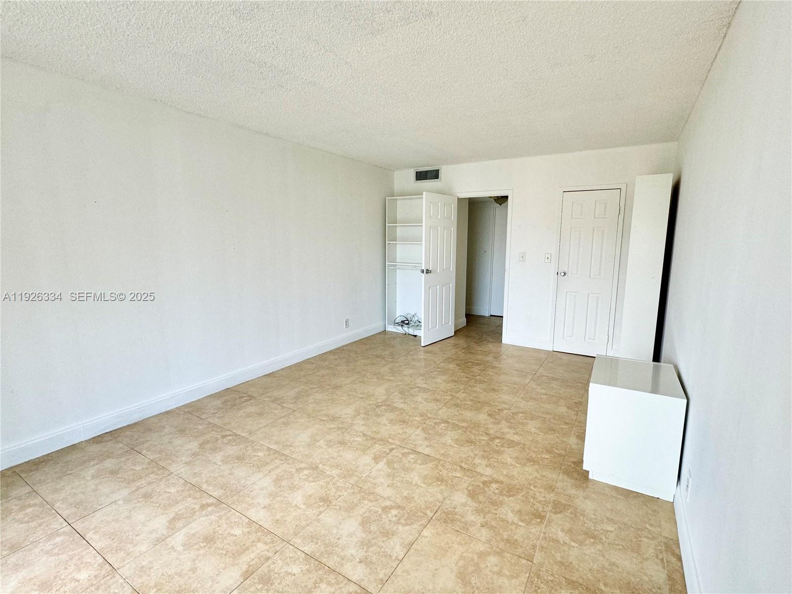An empty room features beige tile flooring, white walls, and two white interior doors — 801 Three Islands Blvd # 417, Hallandale Beach FL 33009, HALLANDALE BEACH, FL