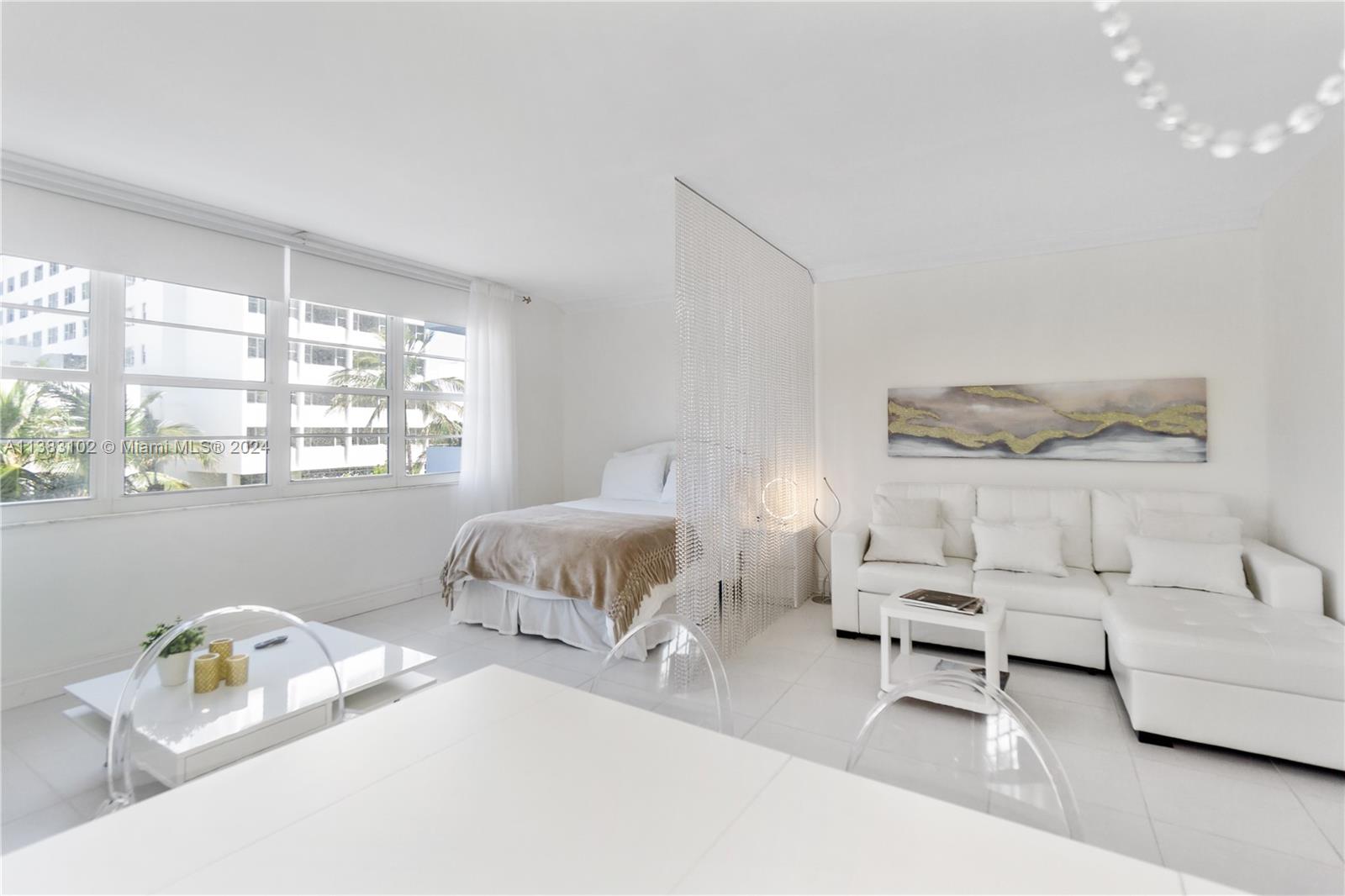 A studio apartment features a white sofa, a bed, and a beaded room divider — 100 Lincoln Rd # 306, Miami Beach FL 33139, MIAMI BEACH, FL