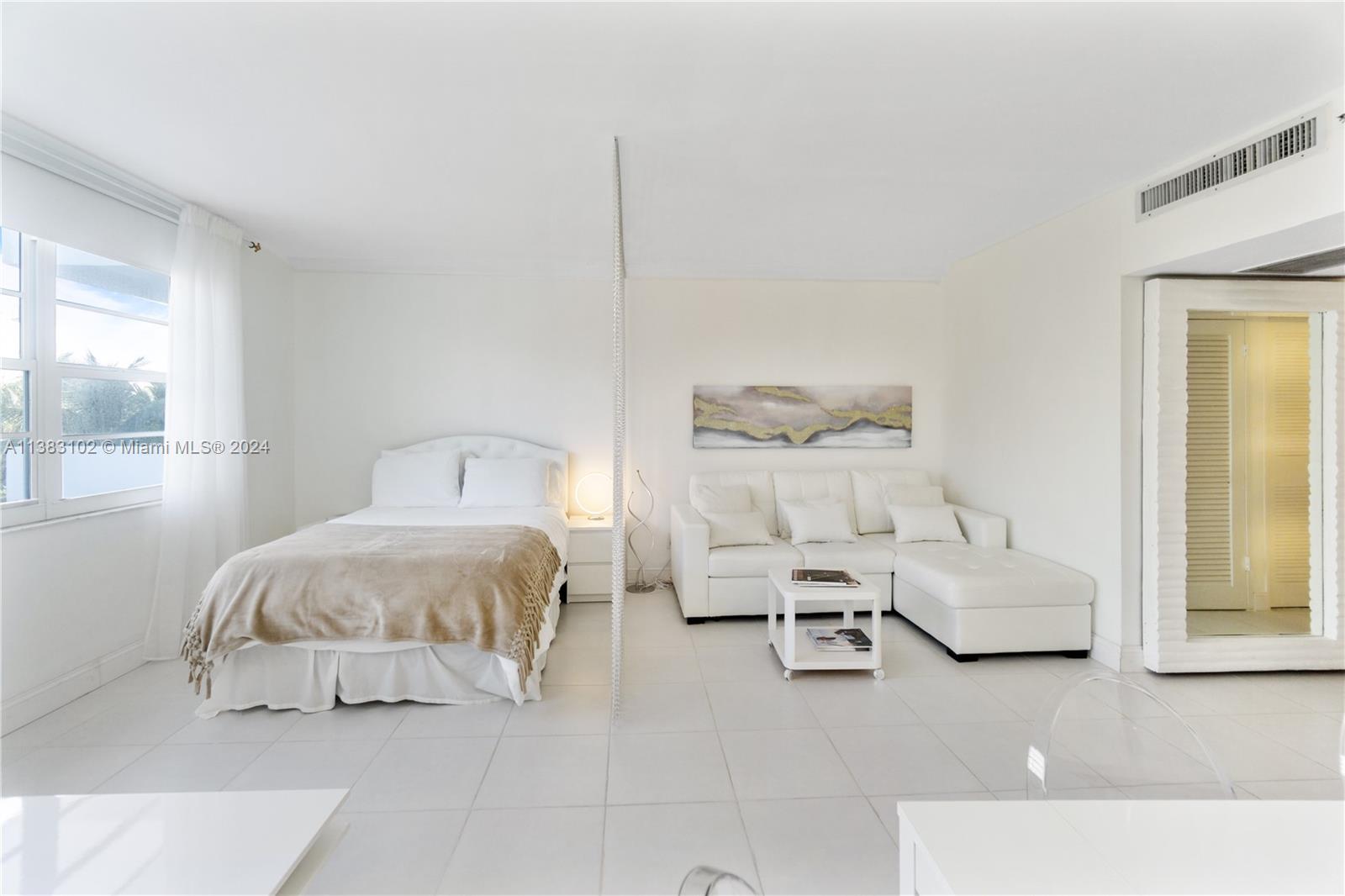 A studio apartment features a bed and white sectional sofa separated by a beaded curtain — 100 Lincoln Rd # 306, Miami Beach FL 33139, MIAMI BEACH, FL