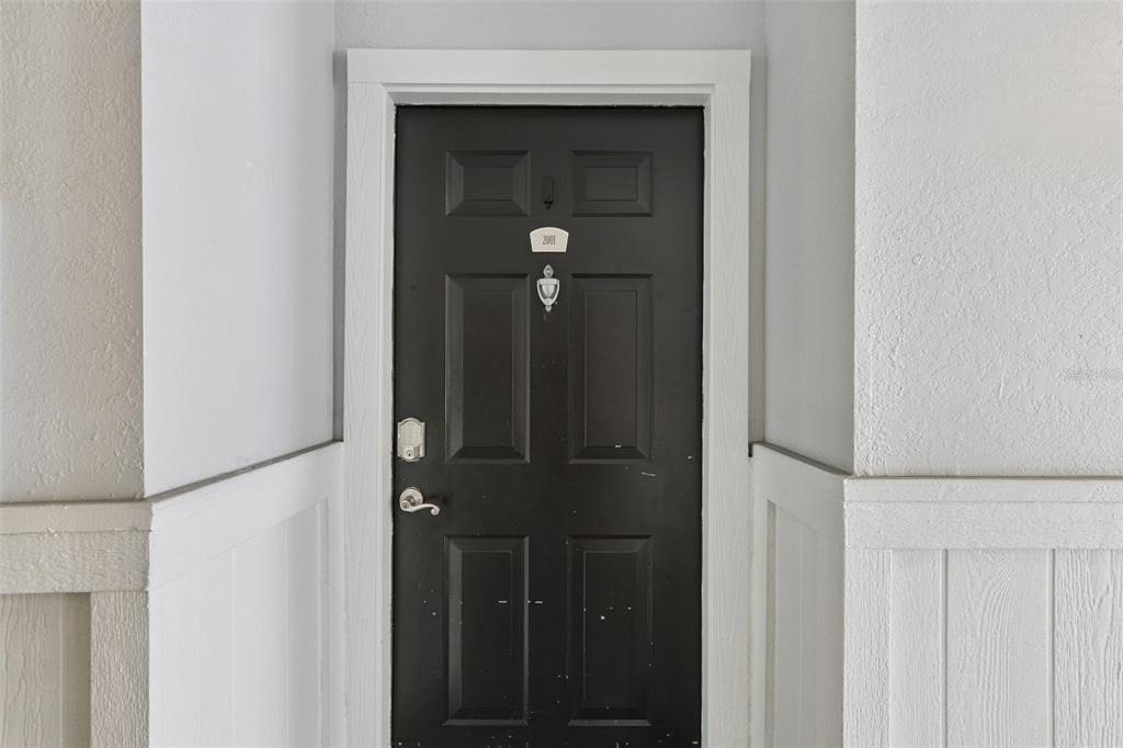A black front door with a silver knocker and handle is set within a white frame — 300 E SOUTH STREET UNIT 2001, ORLANDO, FL