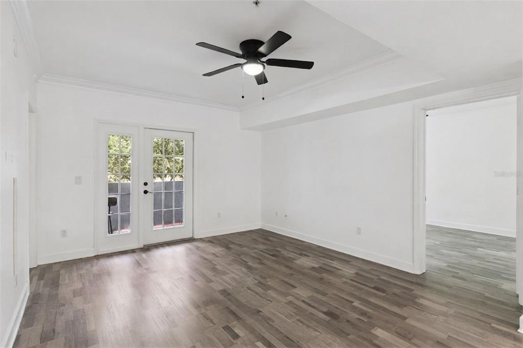 An empty room with white walls, wood-look flooring, a ceiling fan, and glass-paned double doors — 300 E SOUTH STREET UNIT 2001, ORLANDO, FL