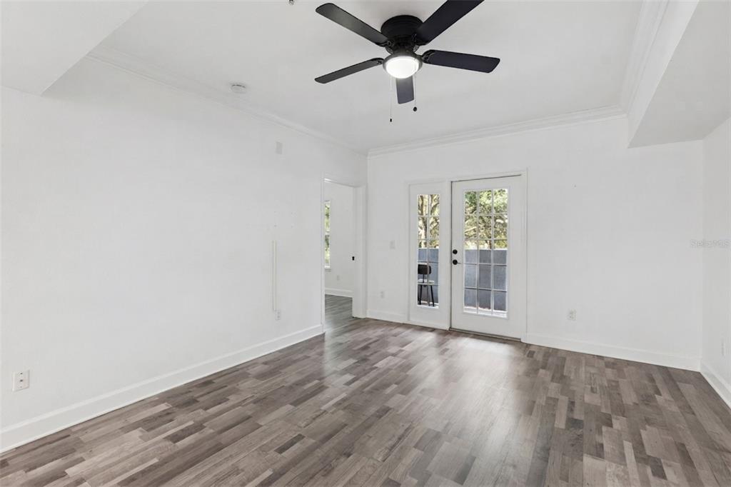 An empty room features white walls, gray wood-look flooring, a ceiling fan, and glass doors — 300 E SOUTH STREET UNIT 2001, ORLANDO, FL