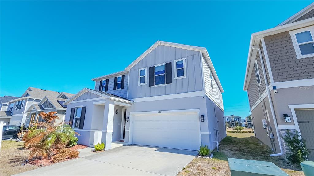 A two-story house with a light blue exterior, a two-car garage, and a concrete driveway — 895 OVERPOOL AVENUE, DAVENPORT, FL