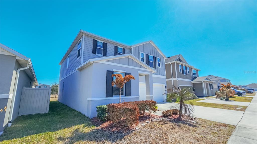 A two-story suburban house with light gray siding, dark shutters, and a two-car garage — 895 OVERPOOL AVENUE, DAVENPORT, FL