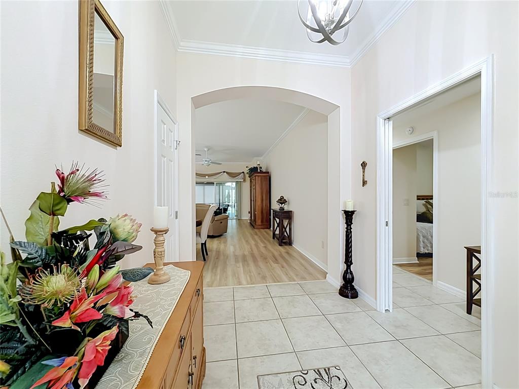 A tiled foyer leads through an arched doorway into a living area with wood flooring — 1967 FLOWERSVILLE PLACE, THE VILLAGES, FL