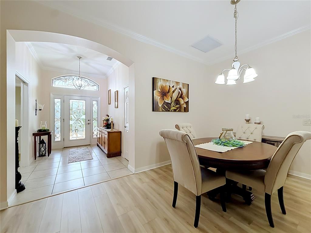 A dining area with a round table and chairs opens into a tiled entryway — 1967 FLOWERSVILLE PLACE, THE VILLAGES, FL