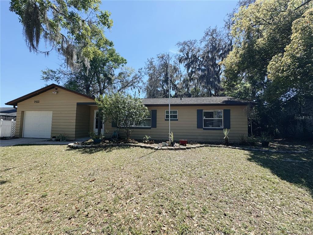 A single-story house with tan siding, a garage, and a large front yard — 7522 LAUREL SPRINGS DRIVE, WINTER PARK, FL