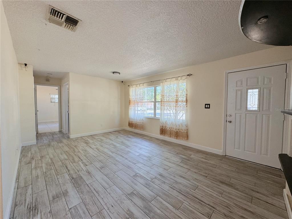 A living room with light-colored tile flooring, white walls, a front door, and a window — 7522 LAUREL SPRINGS DRIVE, WINTER PARK, FL