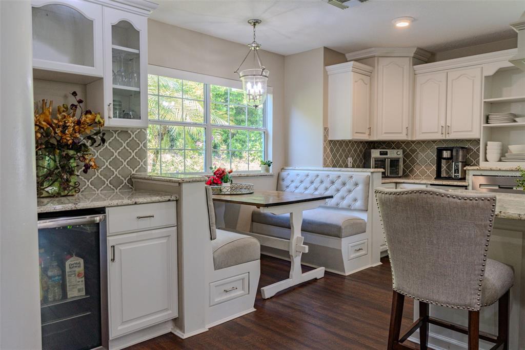 A kitchen breakfast nook features a built-in banquette, a wooden table, and white cabinetry — 33721 SPRING DRIVE, LEESBURG, FL