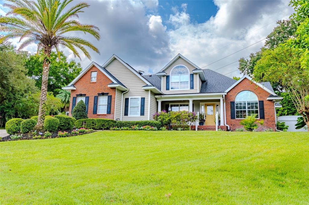 A two-story house with a brick and siding exterior sits behind a large green lawn — 33721 SPRING DRIVE, LEESBURG, FL