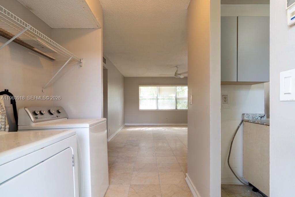 A laundry area with a washer and dryer leads into a tiled living space — 550 SE 2nd Ave # G25, Deerfield Beach FL 33441, DEERFIELD BEACH, FL