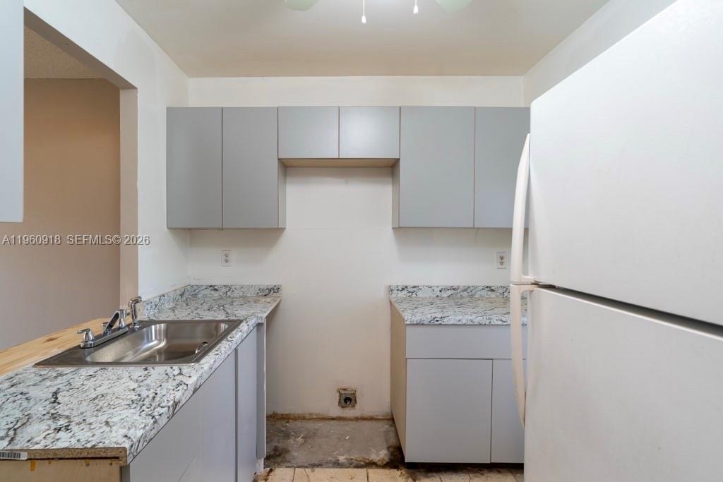 A kitchen features gray cabinets, granite-look countertops, a stainless steel sink, and a missing appliance — 550 SE 2nd Ave # G25, Deerfield Beach FL 33441, DEERFIELD BEACH, FL