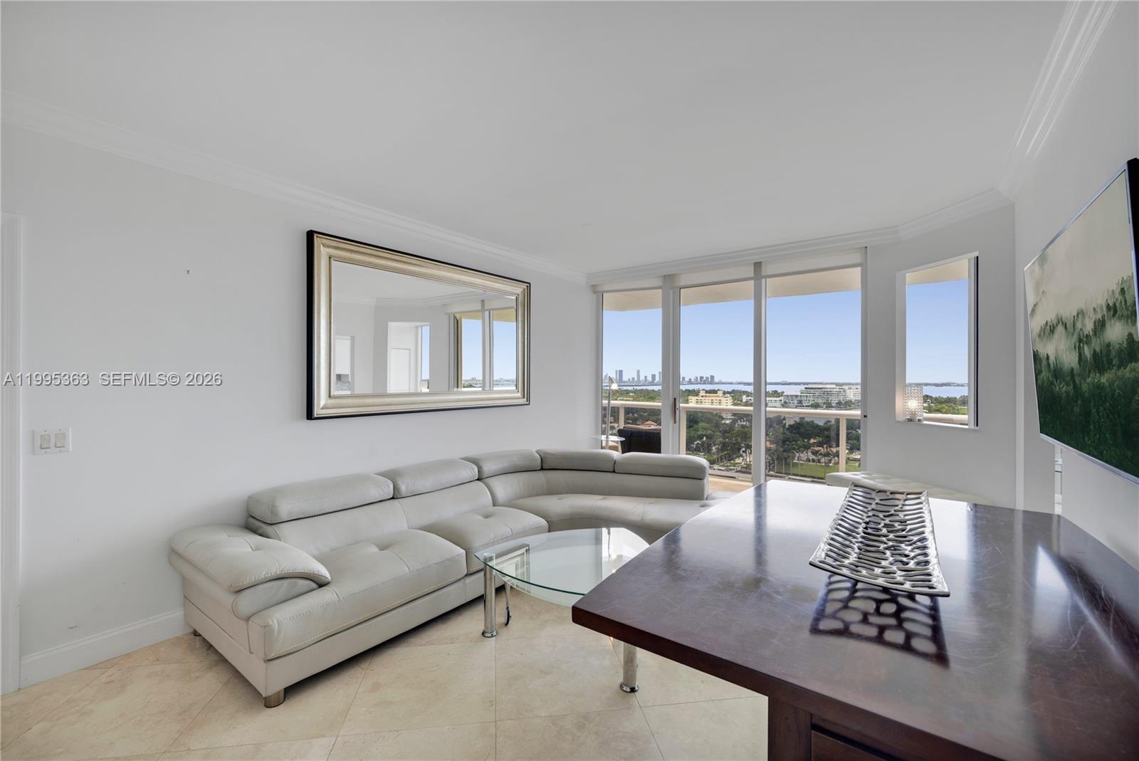 A living room features a light-colored sectional sofa, a glass coffee table, and a balcony — 4779 Collins Ave # 1706, Miami Beach FL 33140, MIAMI BEACH, FL