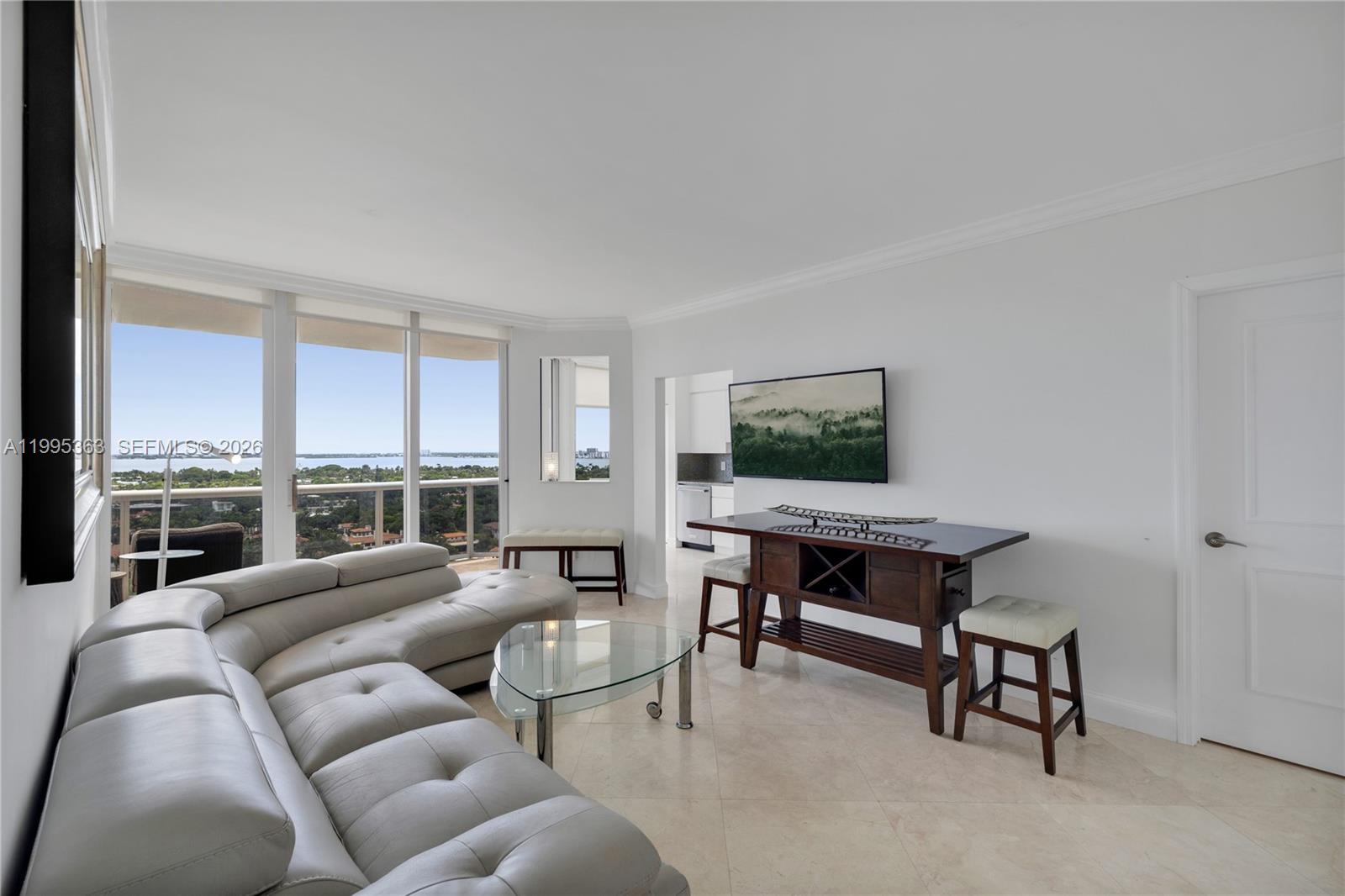 A living room features a curved leather sofa, glass coffee table, and a dining console — 4779 Collins Ave # 1706, Miami Beach FL 33140, MIAMI BEACH, FL