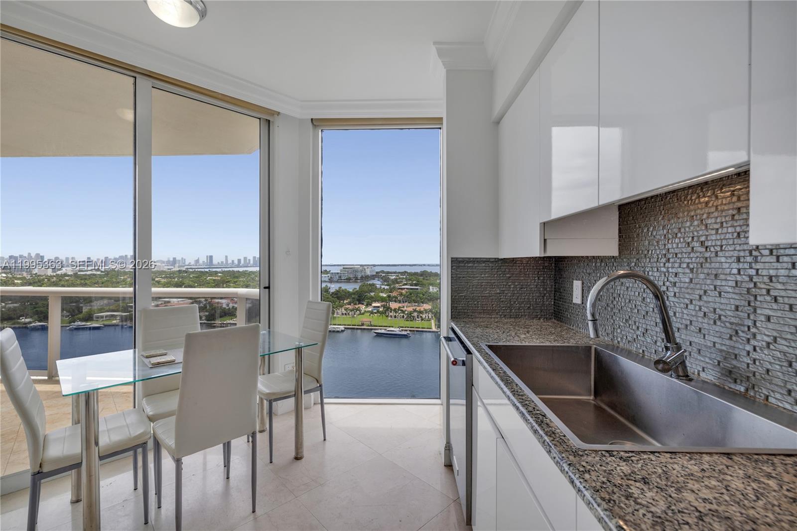 A kitchen with granite countertops and a dining area overlooking a bay and city skyline — 4779 Collins Ave # 1706, Miami Beach FL 33140, MIAMI BEACH, FL