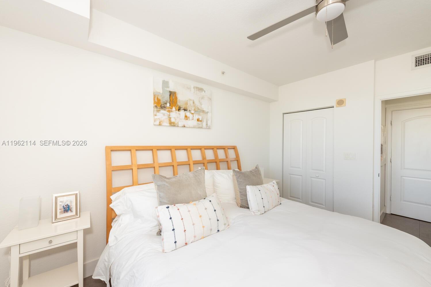 A bedroom features a wooden headboard, white bedding, a ceiling fan, and a closet — 1830 Radius Dr # 709, Hollywood FL 33020, HOLLYWOOD, FL