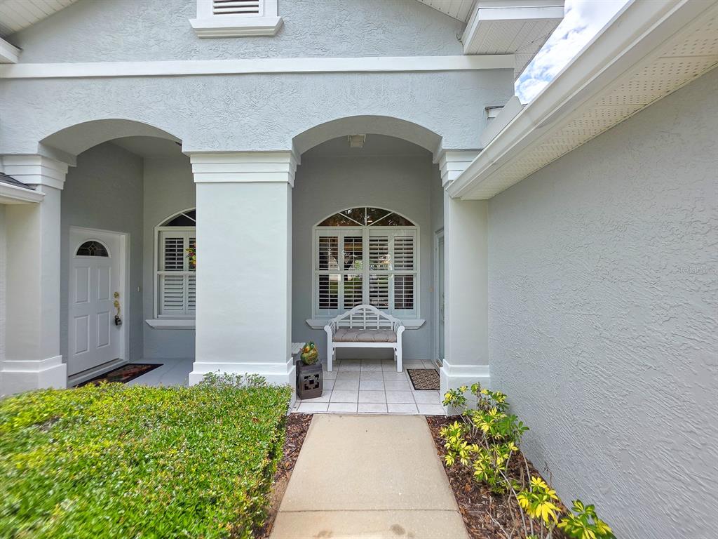 A concrete walkway leads to a covered entryway with two arched openings and a bench — 3137 KAILANI COURT, ORMOND BEACH, FL