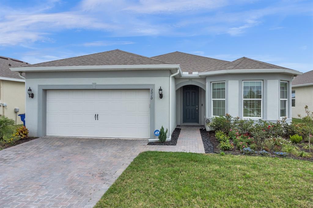 A single-story house features a two-car garage, a paved driveway, and a front entryway — 2010 SPRING SHOWER CIRCLE, KISSIMMEE, FL