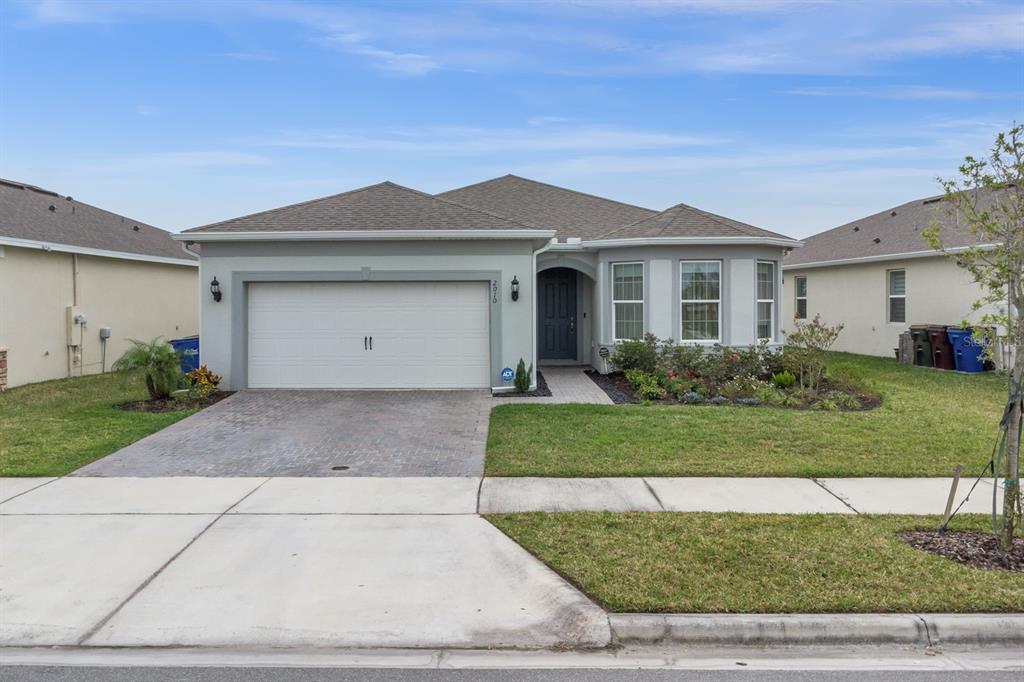 A single-story house with a two-car garage, a paved driveway, and a landscaped front yard — 2010 SPRING SHOWER CIRCLE, KISSIMMEE, FL