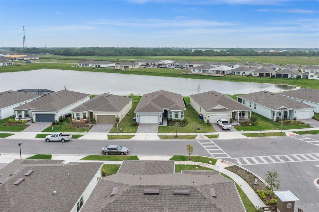 An aerial view shows a row of suburban houses facing a pond and road — 2010 SPRING SHOWER CIRCLE, KISSIMMEE, FL