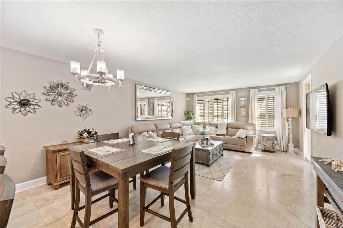 A dining area with a wooden table and chairs opens into a living room space — 3475 S Ocean Boulevard # 1030, Palm Beach FL 33480, PALM BEACH, FL