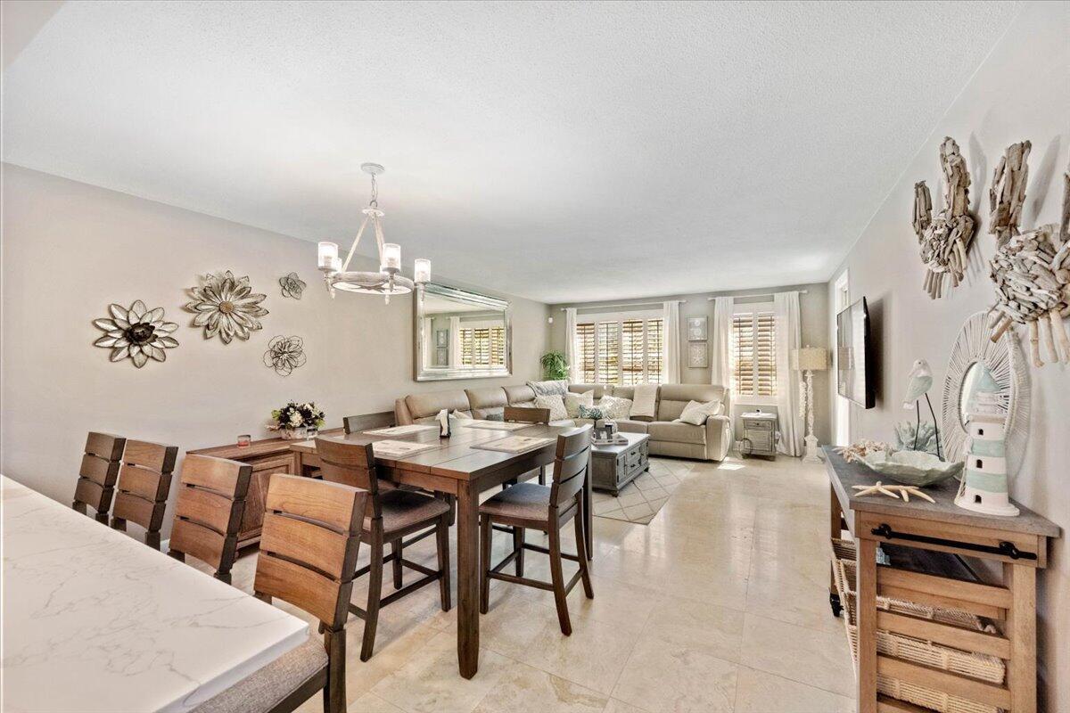 An open-concept living and dining area features tile flooring, wood furniture, and coastal wall decor — 3475 S Ocean Boulevard # 1030, Palm Beach FL 33480, PALM BEACH, FL