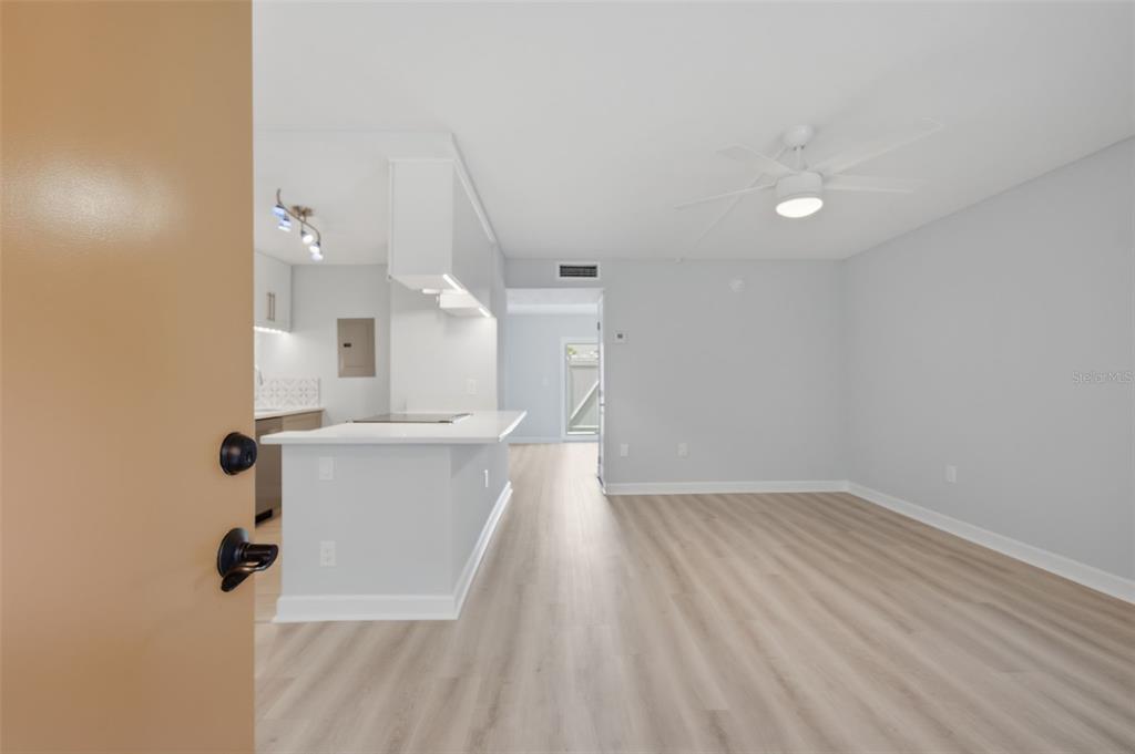 An open-concept living area features light wood-look flooring, a white kitchen island, and a ceiling fan — 8931 BLIND PASS ROAD UNIT 157, ST PETE BEACH, FL