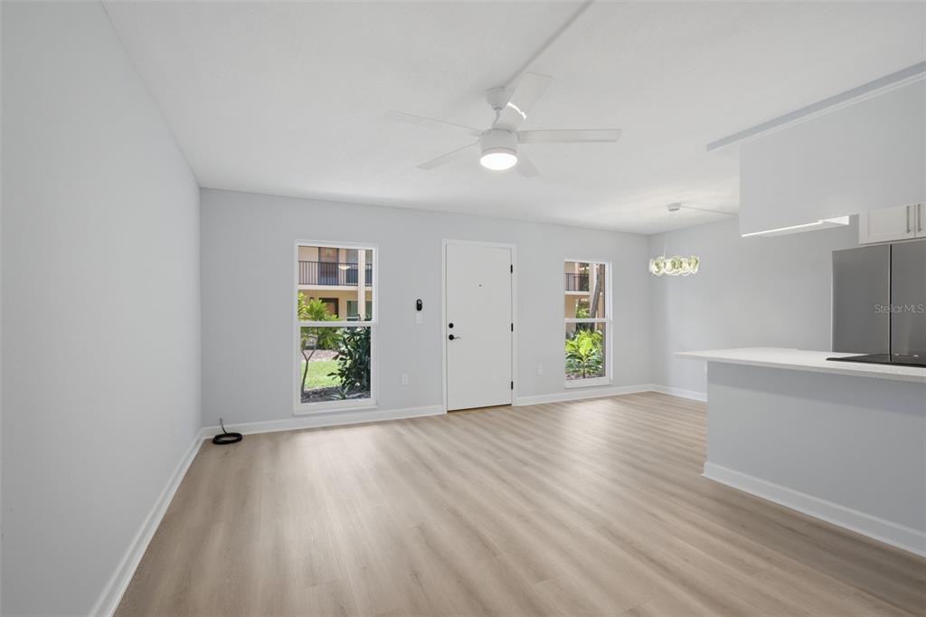 A bright, open-concept living area features light wood-look flooring, a ceiling fan, and white walls — 8931 BLIND PASS ROAD UNIT 157, ST PETE BEACH, FL