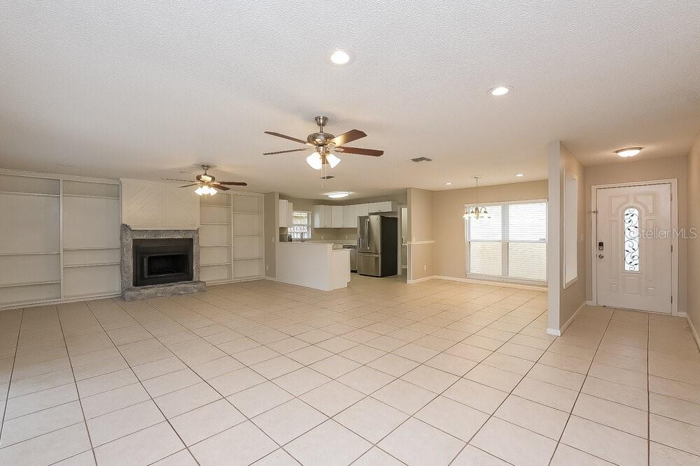 An open-concept living room and kitchen featuring tile flooring, a fireplace, and ceiling fans — 15709 SQUIRREL TREE PLACE, TAMPA, FL