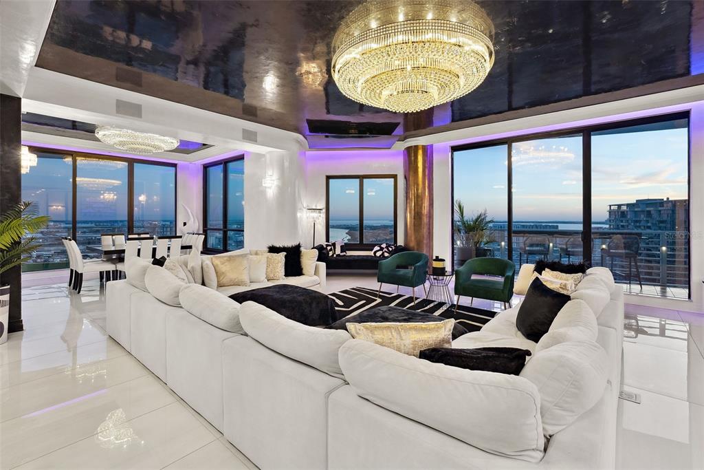 A modern living room features a large white sectional, crystal chandeliers, and floor-to-ceiling windows — 1209 E CUMBERLAND AVENUE UNIT 2601, TAMPA, FL