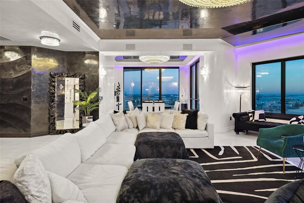 A modern living room features a large white sectional, dark accents, and floor-to-ceiling windows — 1209 E CUMBERLAND AVENUE UNIT 2601, TAMPA, FL