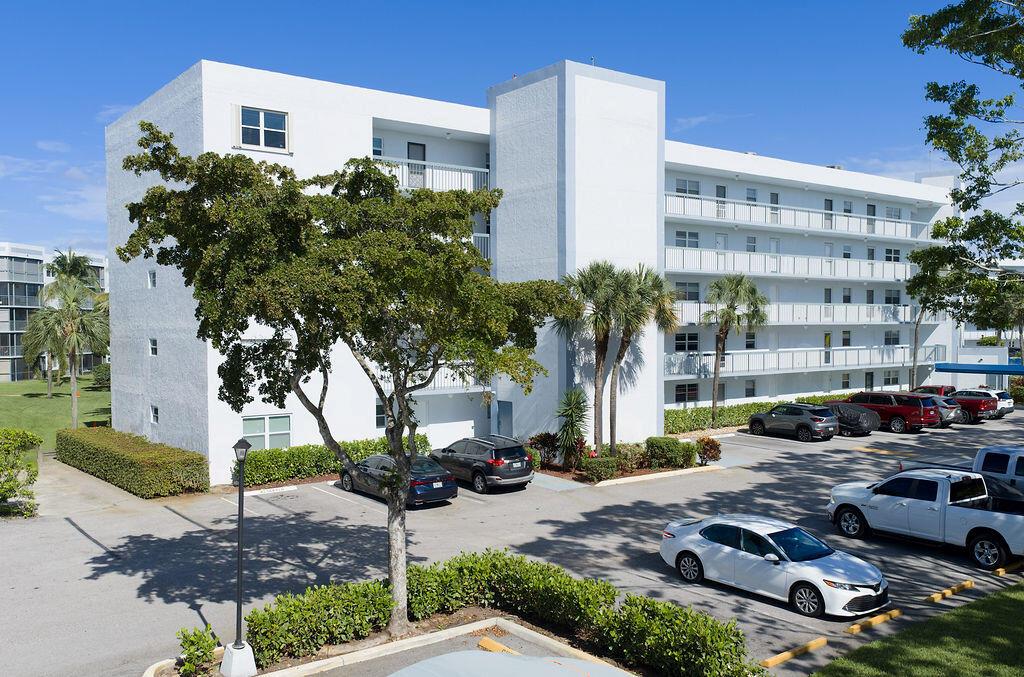 A multi-story white apartment building with balconies and a parking lot in the foreground — 6500 NW 2nd Avenue # 509, Boca Raton FL 33487, BOCA RATON, FL