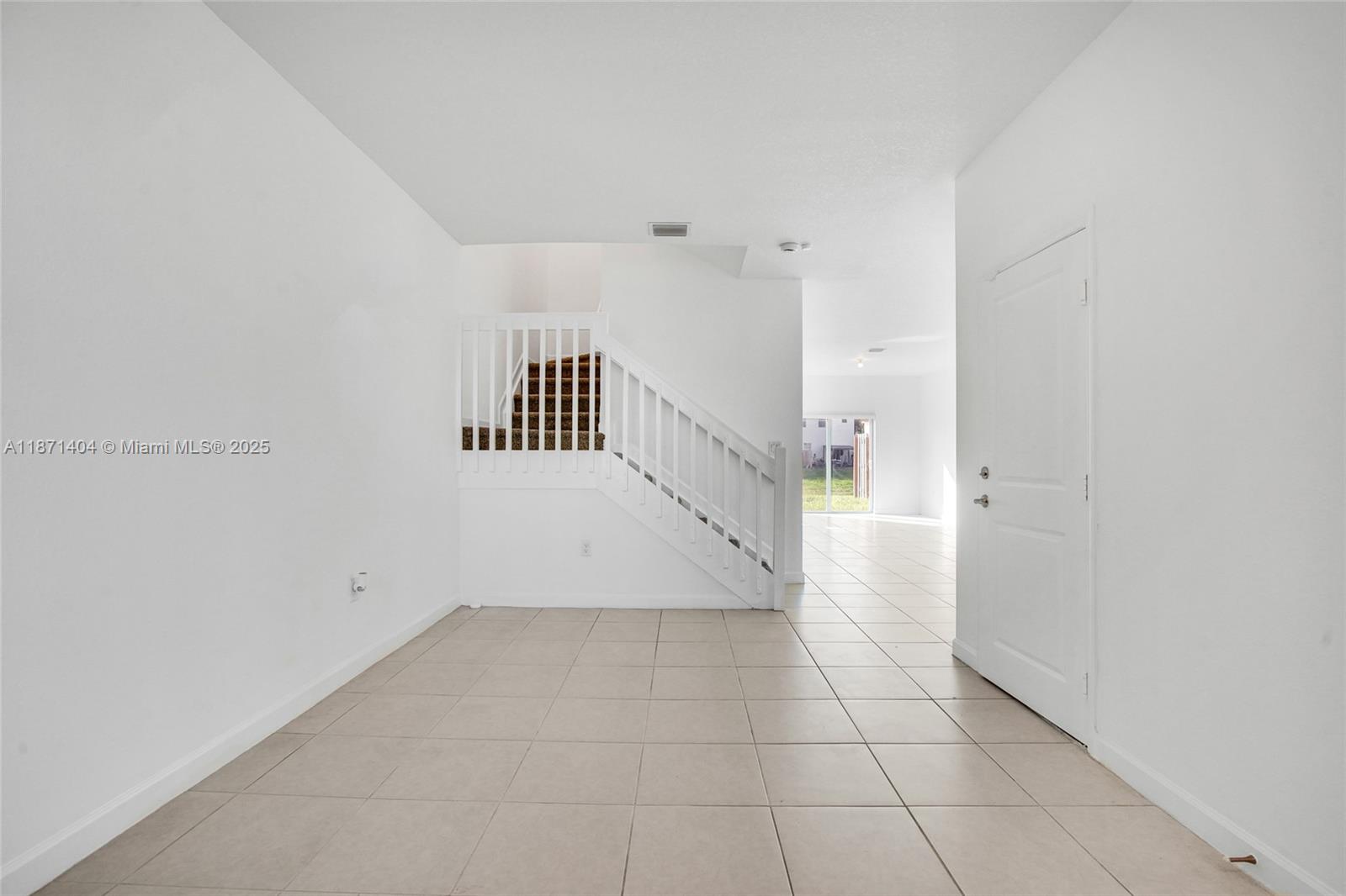 A tiled entryway features a white staircase with a wooden handrail and a closed door — 12609 NW 23rd Pl, Miami FL 33167, MIAMI, FL