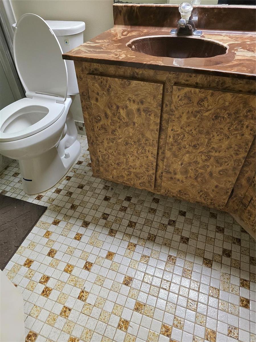 A bathroom features a burl wood vanity, a brown marble countertop, and patterned tile flooring — 12730 SW 112th Street, Miami FL 33186, MIAMI, FL