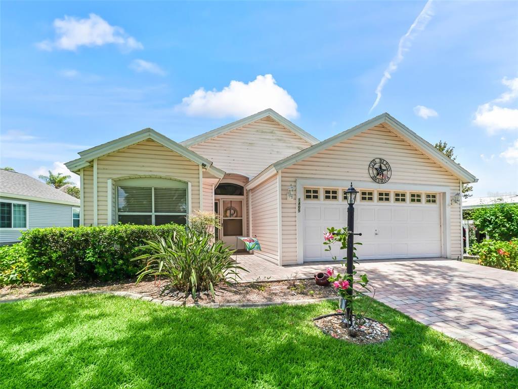 A single-story house with light siding, a two-car garage, and a paved driveway — 1405 W SCHWARTZ BOULEVARD, THE VILLAGES, FL