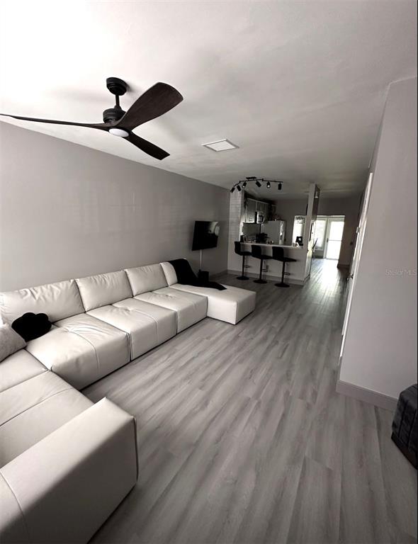 A living room with a white sectional sofa, wood-look flooring, and an open kitchen area — 6210 BAYSIDE KEY DRIVE, TAMPA, FL