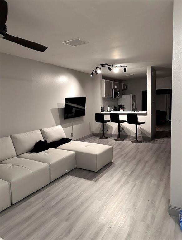 A living room features a large white sectional sofa, light wood-look flooring, and a ceiling fan — 6210 BAYSIDE KEY DRIVE, TAMPA, FL