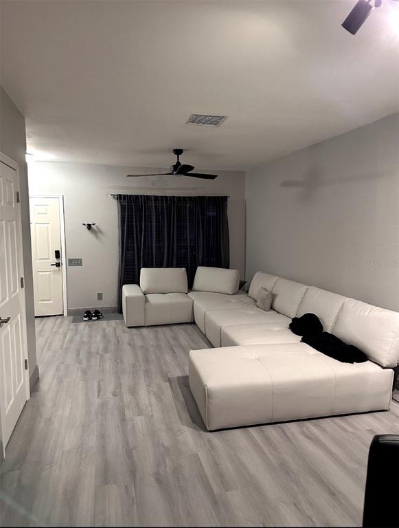 A living room features light wood-look flooring, a white sectional sofa, and a ceiling fan — 6210 BAYSIDE KEY DRIVE, TAMPA, FL
