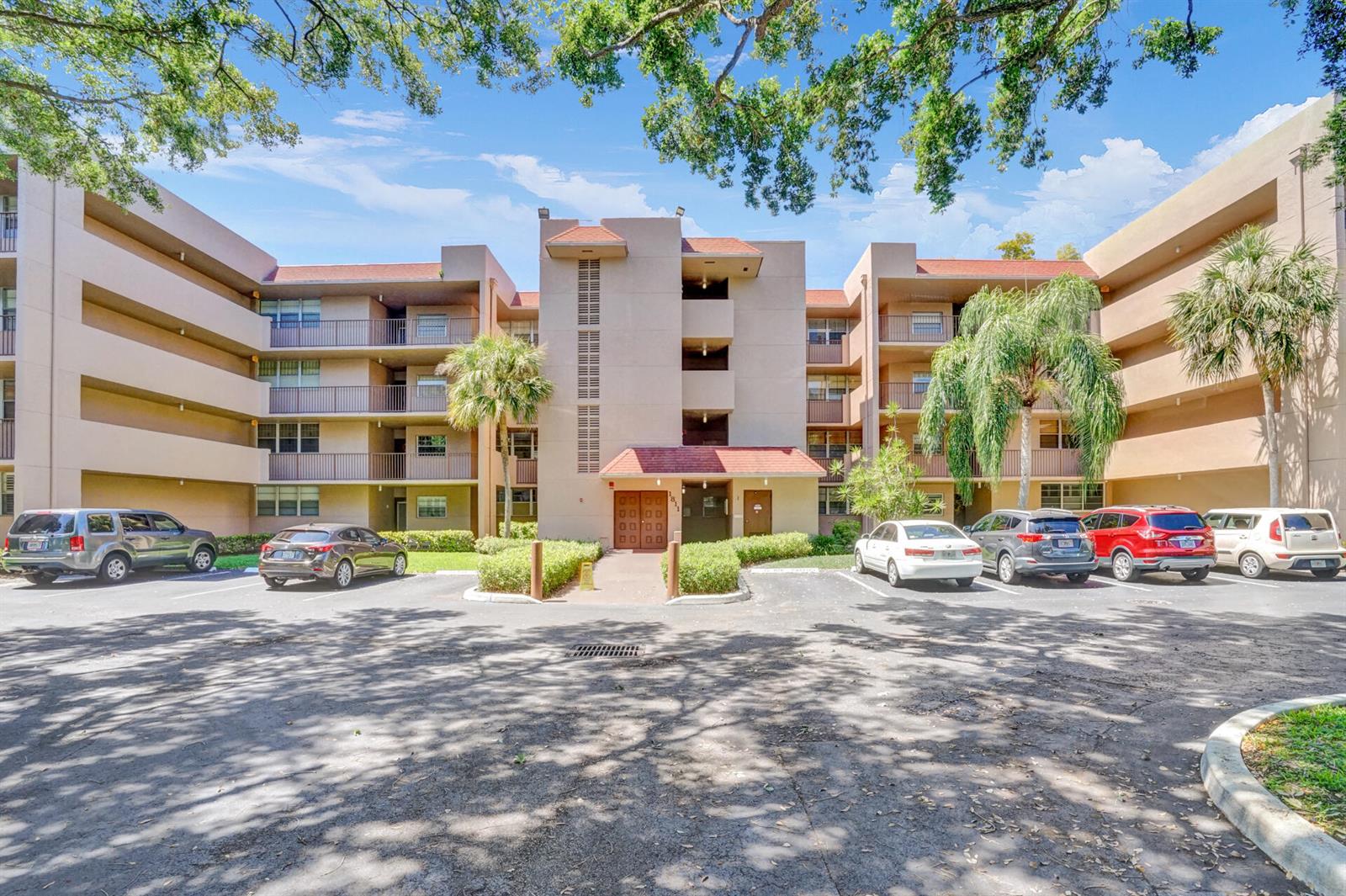 A multi-story apartment building with a central entrance and a parking lot in front — 1811 Sabal Palm Drive # 203, Davie FL 33324, DAVIE, FL