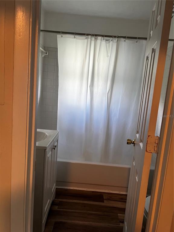 A bathroom features a white vanity, a bathtub with a shower curtain, and wood-look flooring — 408 NE 18 STREET, GAINESVILLE, FL