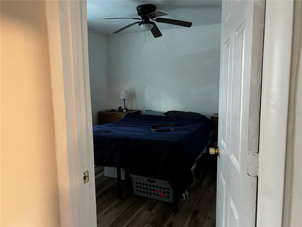 A bedroom with a dark blue bedspread, a ceiling fan, and wood-look flooring — 408 NE 18 STREET, GAINESVILLE, FL
