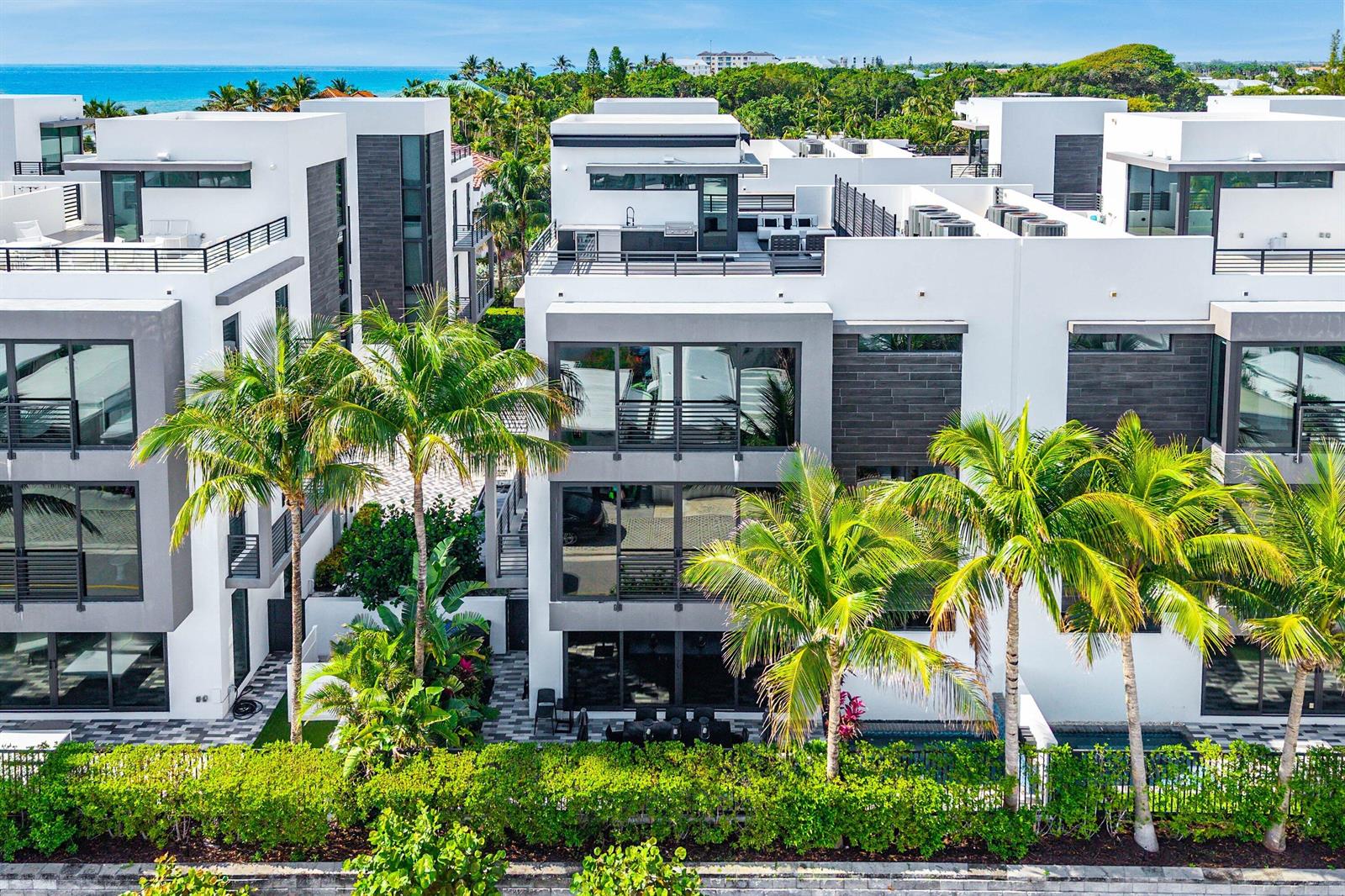 Exterior view of modern multi-story townhouses with flat roofs, balconies, and palm trees — 11501 Old Ocean Boulevard, Ocean Ridge FL 33435, OCEAN RIDGE, FL