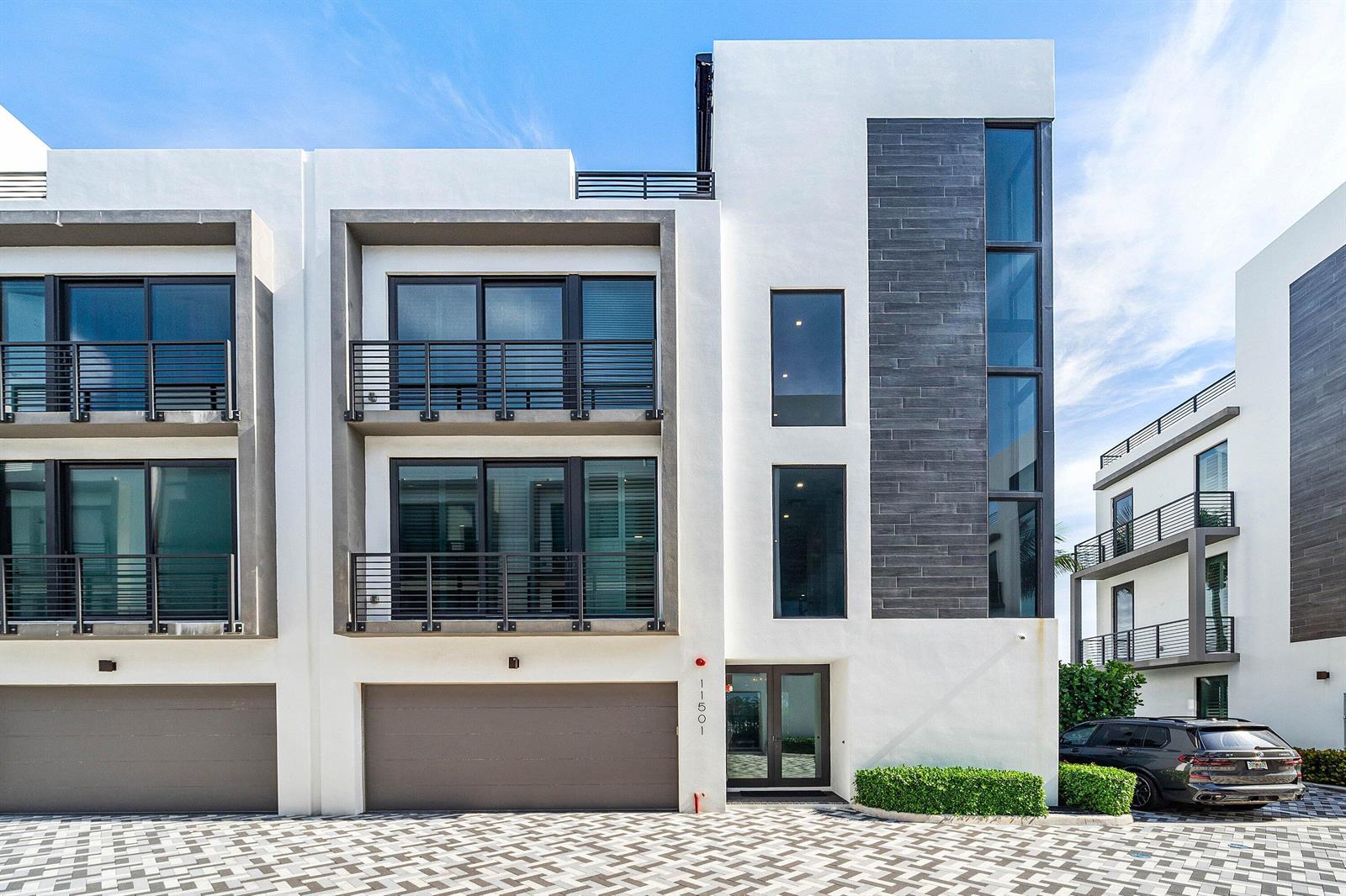 A modern three-story townhouse with white stucco, dark tile accents, balconies, and a garage — 11501 Old Ocean Boulevard, Ocean Ridge FL 33435, OCEAN RIDGE, FL